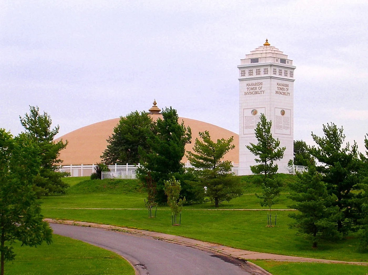 A golden dome and a white tower on a green campus